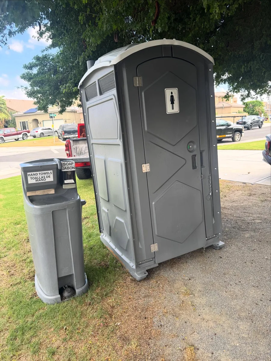 Freestanding handwashing station next to a portable restroom